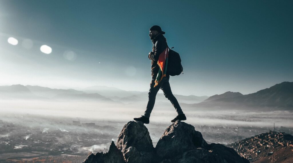 Symbolfoto eines Bergsteigers auf dem Gipfel